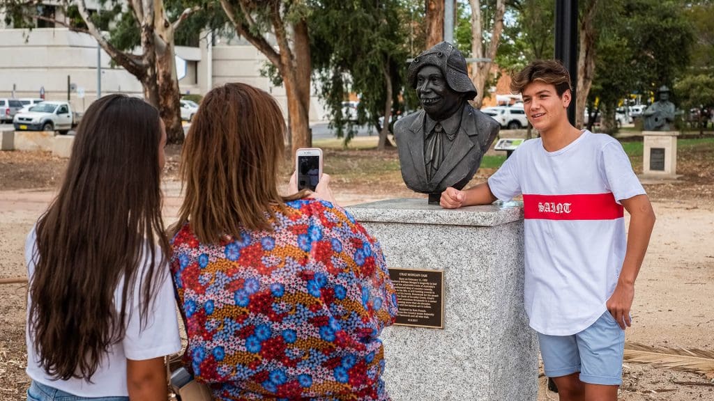 People taking photo with statue of Chad Morgan at Pioneers Parade Tamworth