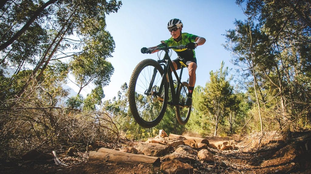 Mountain biker airborne as he jumps a small jump on a dirt track at Tamworth Mountain Bike Park